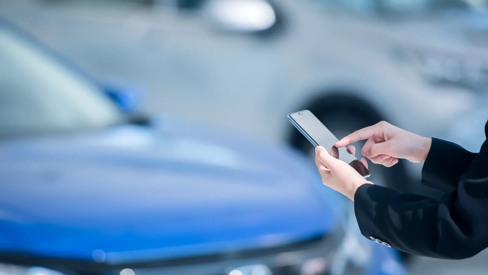 Otomobilin önünde akıllı telefon kullanan eller